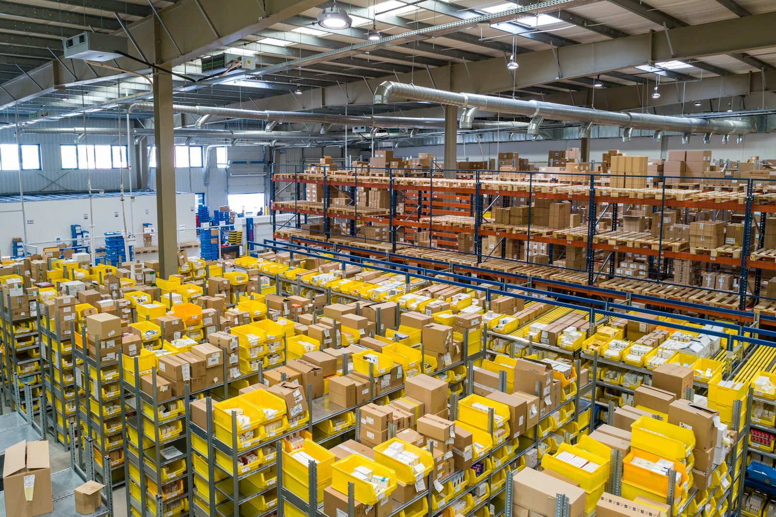 Interior of a fulfillment warehouse with yellow bins and shipping boxes on tall shelves